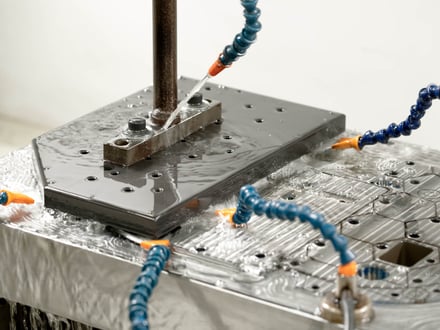 AMP 於冷卻液沖洗下 CNC 加工出口模具,切削模穴、流道與孔位,製程全程於廠內完成