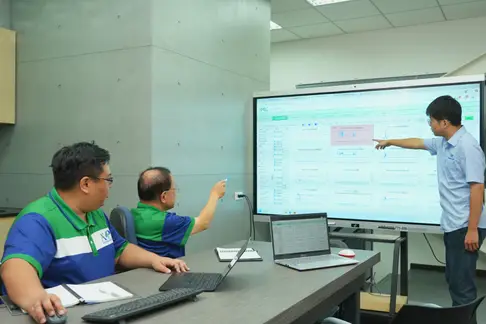 AMP engineers reviewing live injection molding process data on a production-floor monitor